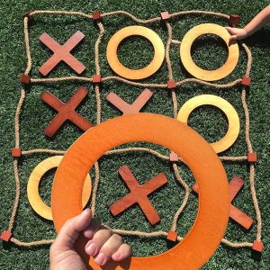 Giant tic-tac-toe - wooden X and O pieces on a rope grid laid out on grass